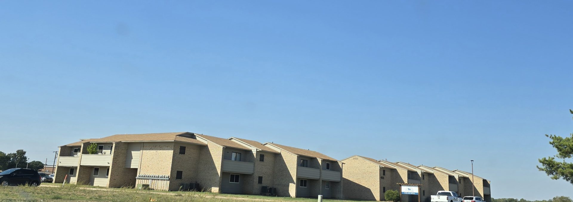 apartment complex with cars parked on the street at The  Courtyard
