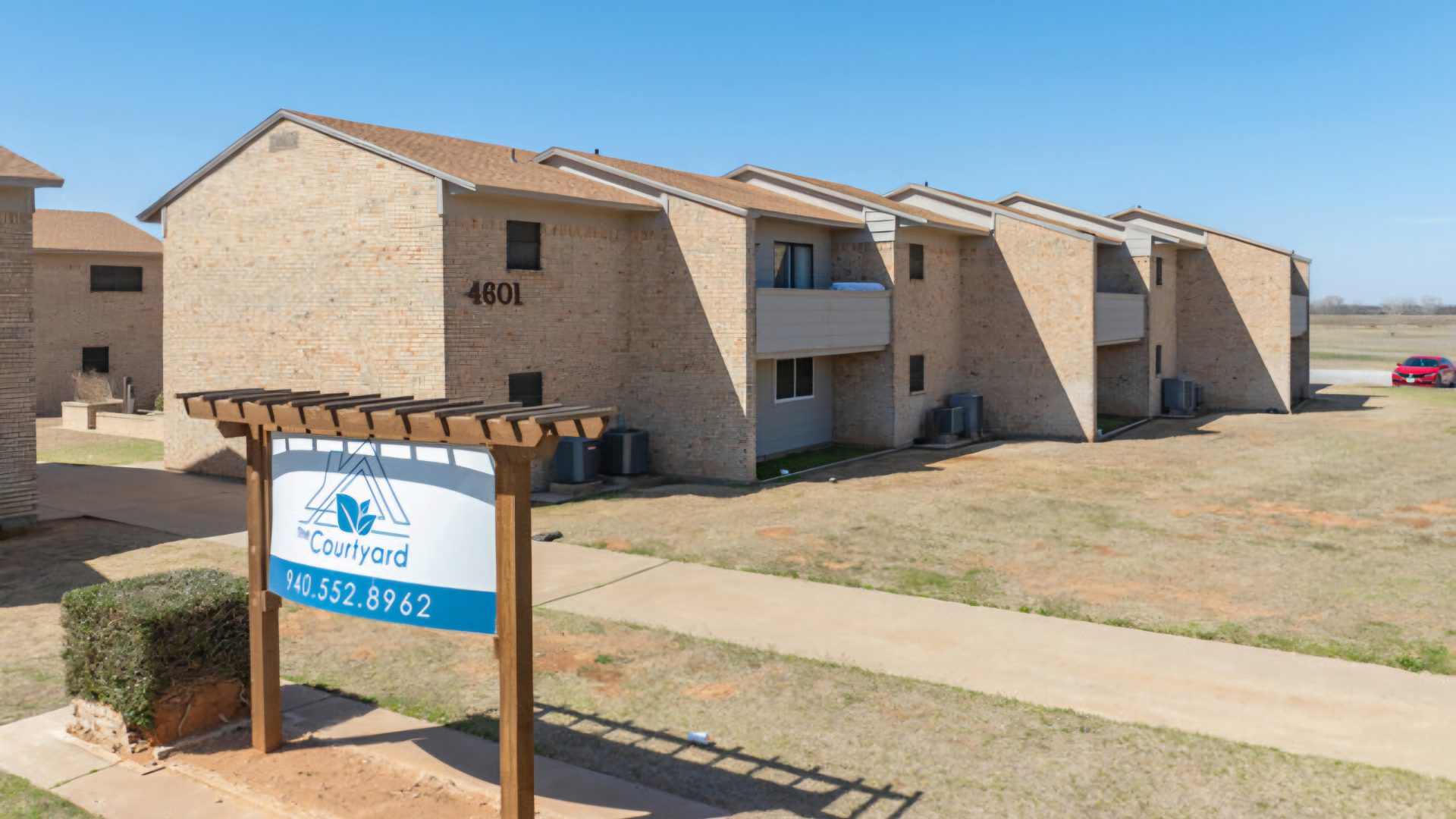the sign for the apartment complex in front of a grassy area at The  Courtyard
