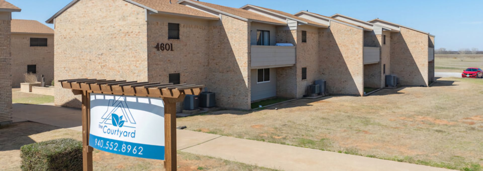the sign for the apartment complex in front of a grassy area at The Courtyard